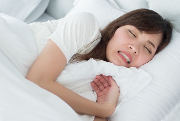 Woman grinding her teeth while sleeping in bed