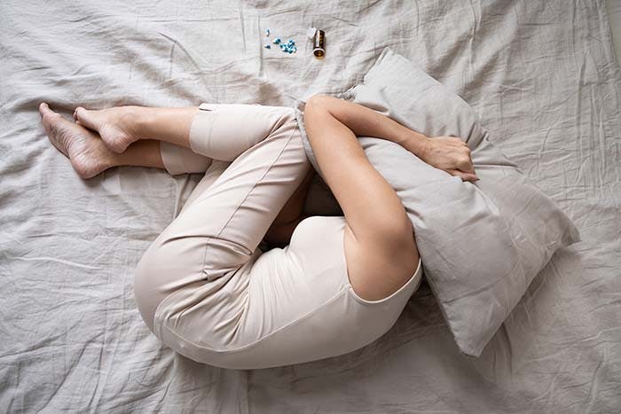 A woman finding difficulty sleeping holding her face in her hands as she lies in bed