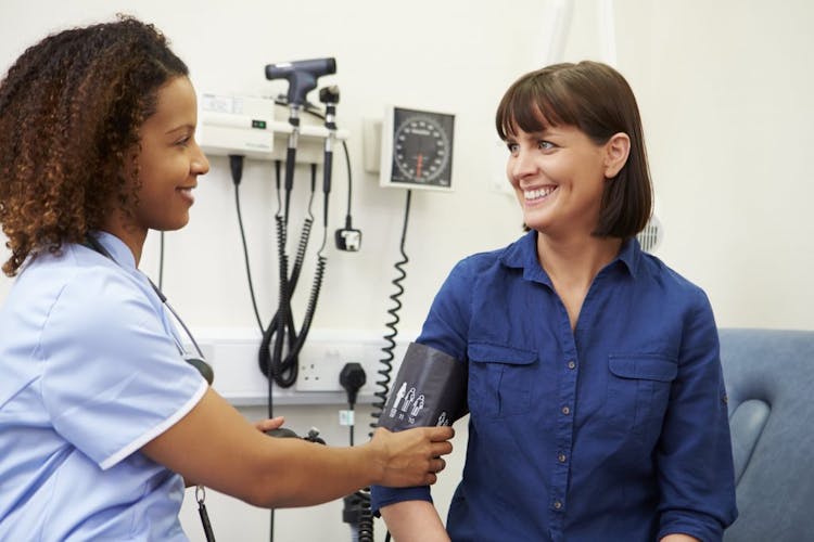 A nurse checks a woman’s blood pressure