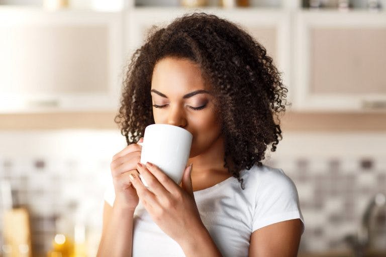 Nice girl drinking tea out of a white mug