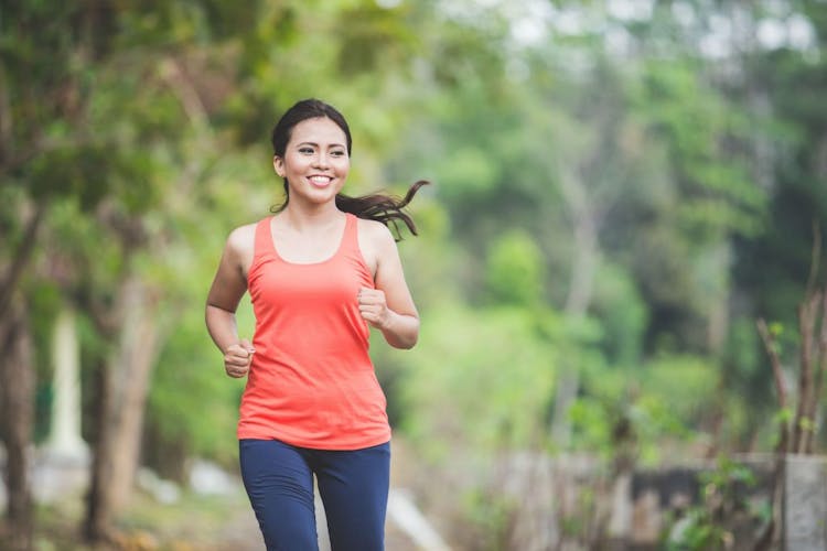 A portrait of a young asian woman doing excercise outdoor in a park, jogging