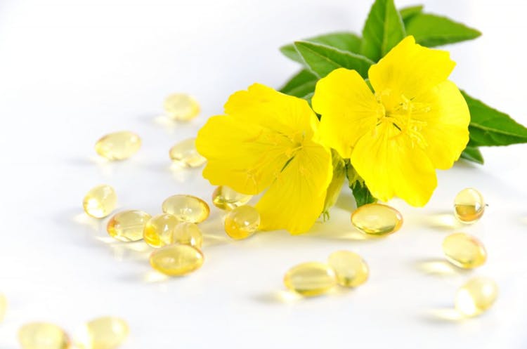 Anti aging supplements in capsule form containing evening primrose oil on a white background with yellow flower