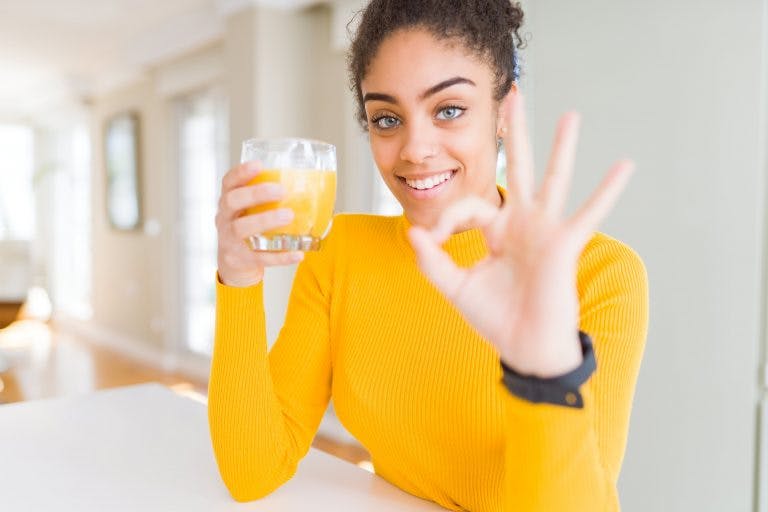 A woman drinking juice for detox cleanse in a living room