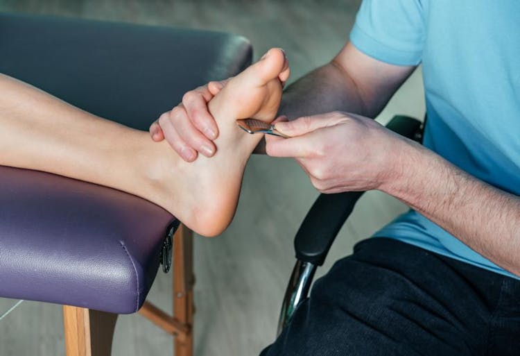 A physical therapist performing scraping on the foot to treat heel pain.