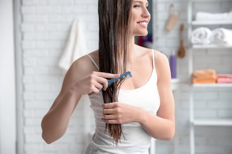 A woman combing her long hair after shower with a thin comb