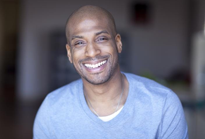 A smiling black man with bald head posing in front of the camera