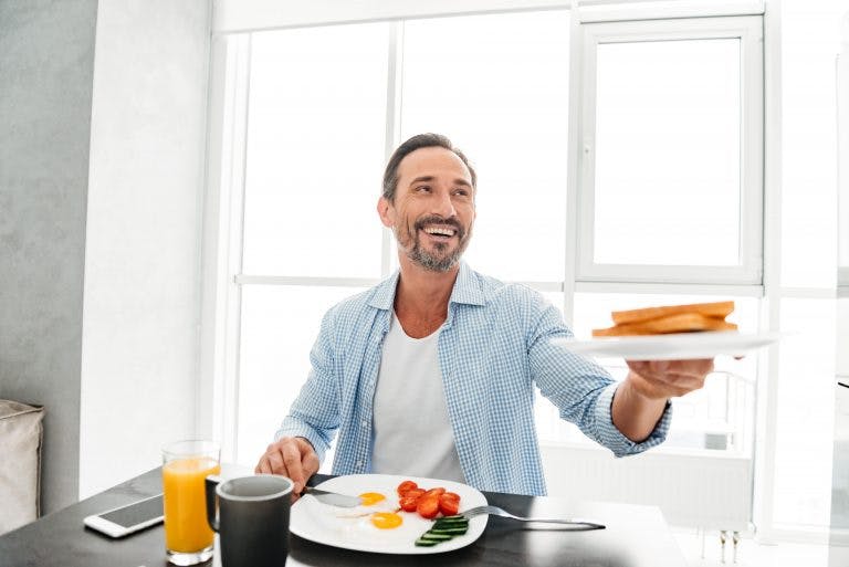 A man having a gluten-free diet breakfast while refusing to eat the bread
