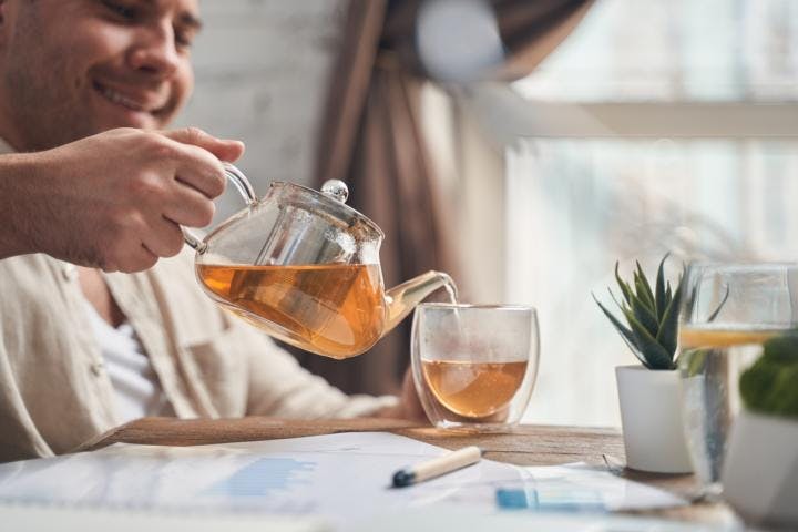 A man pouring himself a cup of chamomile tea as he is working to calm his mind