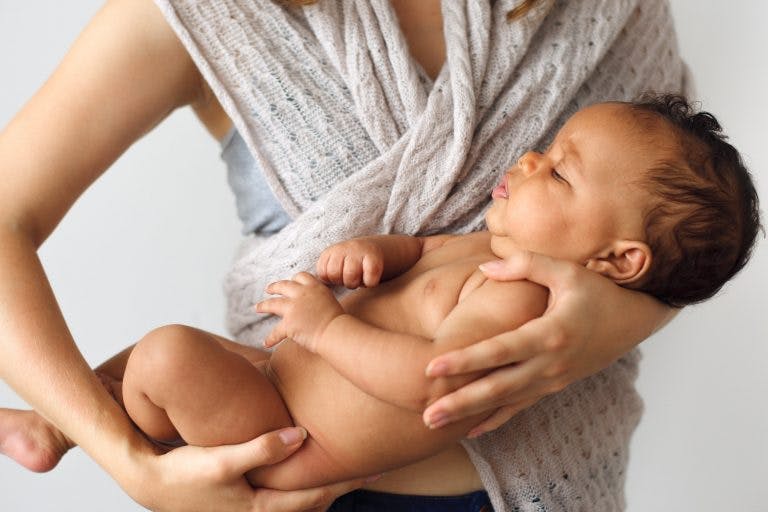 A woman cradling her naked baby on a white background