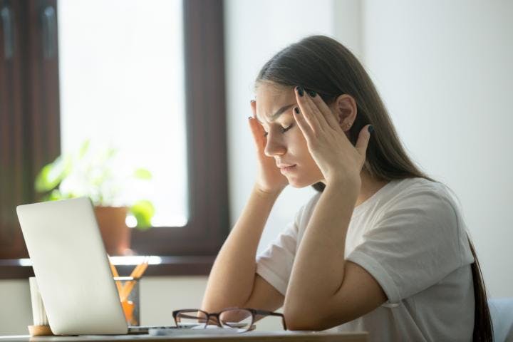A young woman feeling stressed from work at home