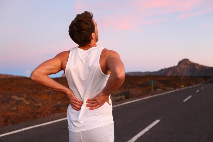 A young man suffering from lower back pain while jogging