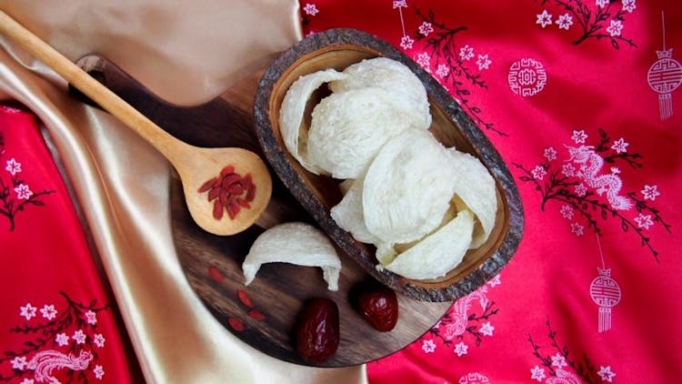 A plate of white bird's nests with goji berries on a red Chinese silk table top