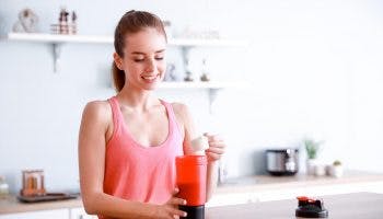 A woman is preparing a collagen peptide drink in her kitchen