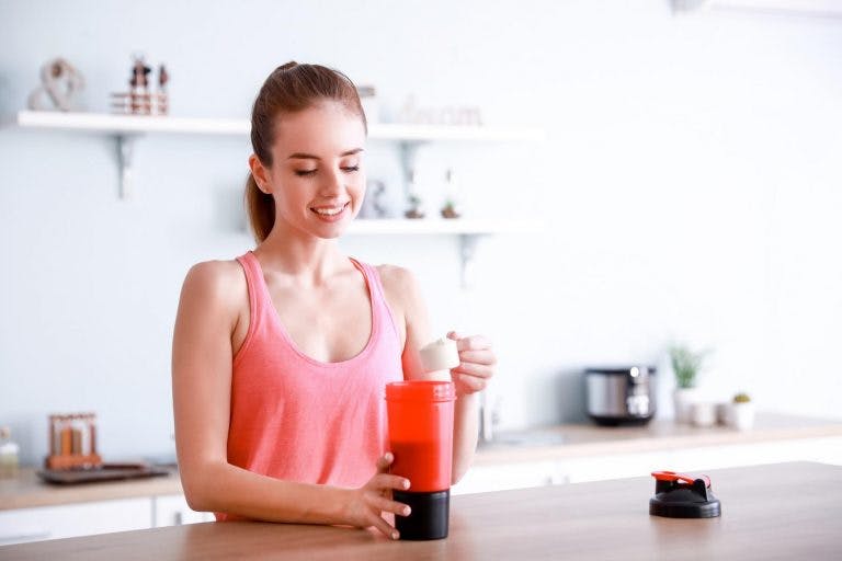 A woman is preparing a collagen peptide drink in her kitchen