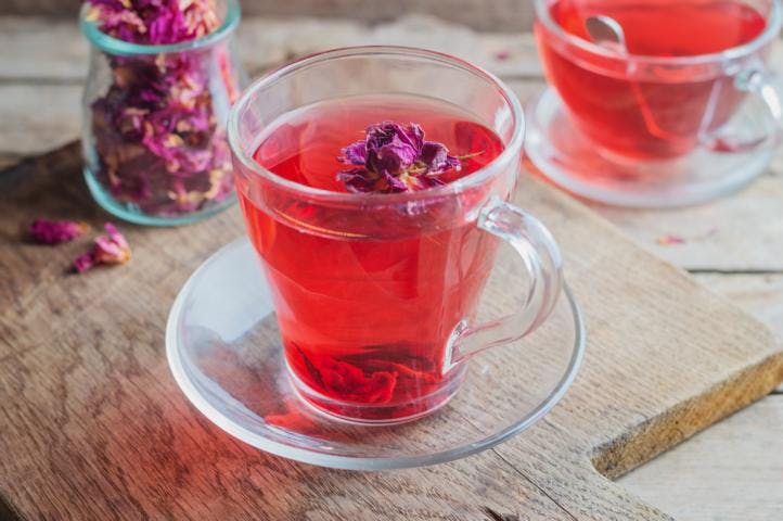 A cup of rose tea with dried rose petals on top