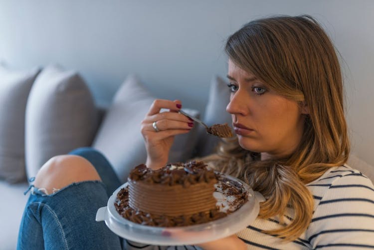 A sad and depressed woman eating chocolate cake