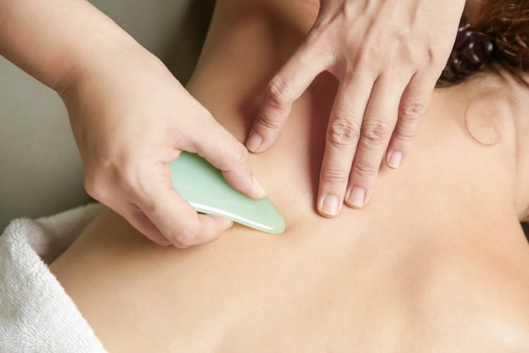 Close-up of a woman having a gua sha massage performed on her back 