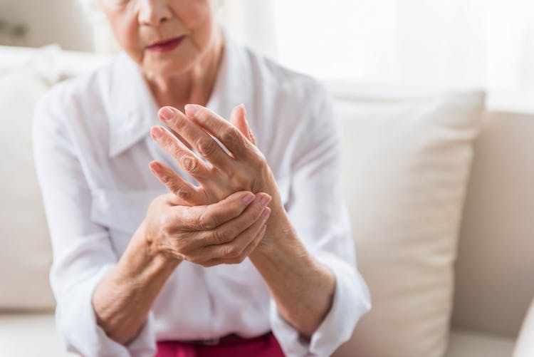 An elderly lady massaging her left hand due to pain or discomfort