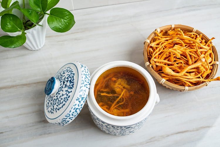 An image of cordyceps mushroom in a bowl and cordyceps tea with other TCM herbs in a porcelain container