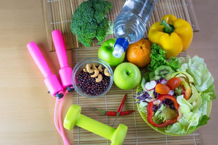 An image of healthy diet foods, a water bottle and exercise equipment