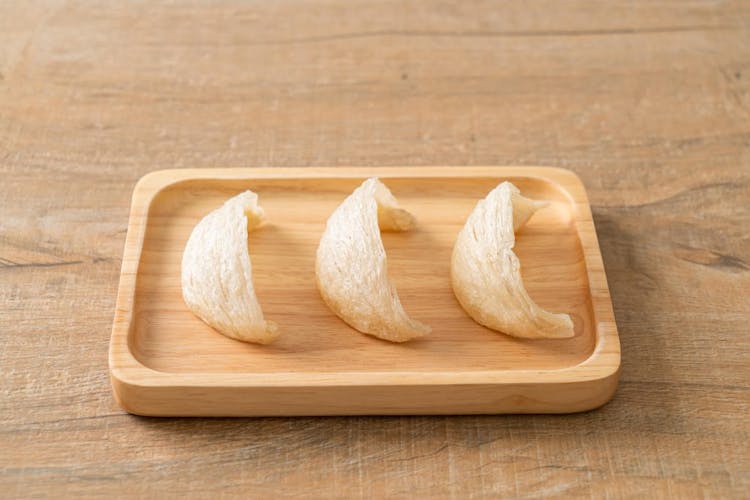 Three pieces of bird's nest on a wooden tray.