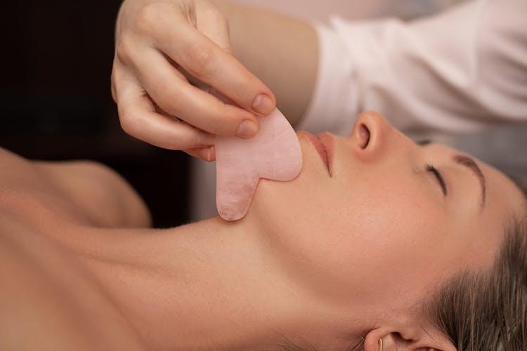 An attractive young woman getting a gua sha facial massage