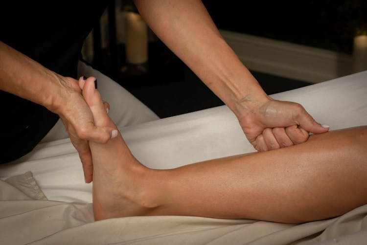 A man giving a deep tissue massage to a woman's shin