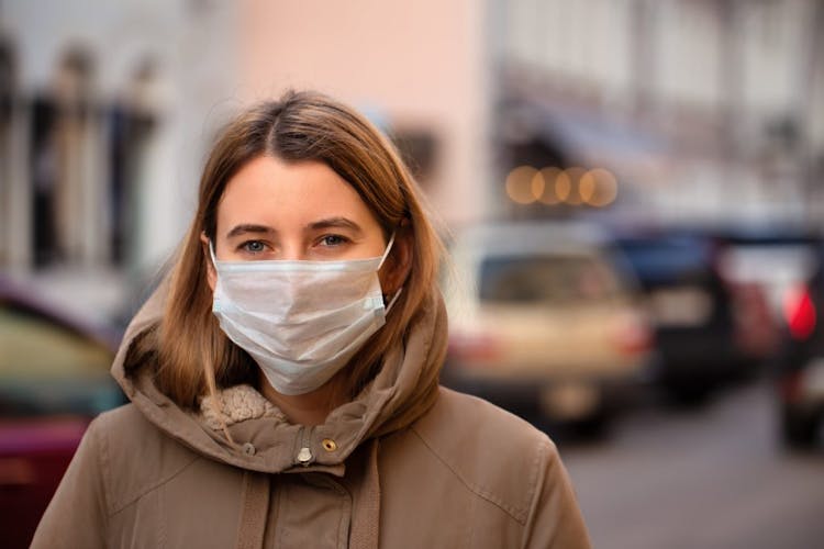 A young woman standing outside wearing a face mask