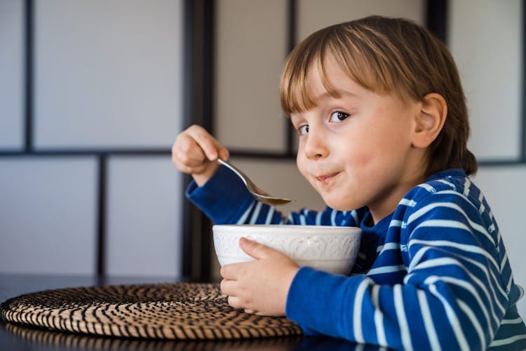 A cute young boy eating soup 