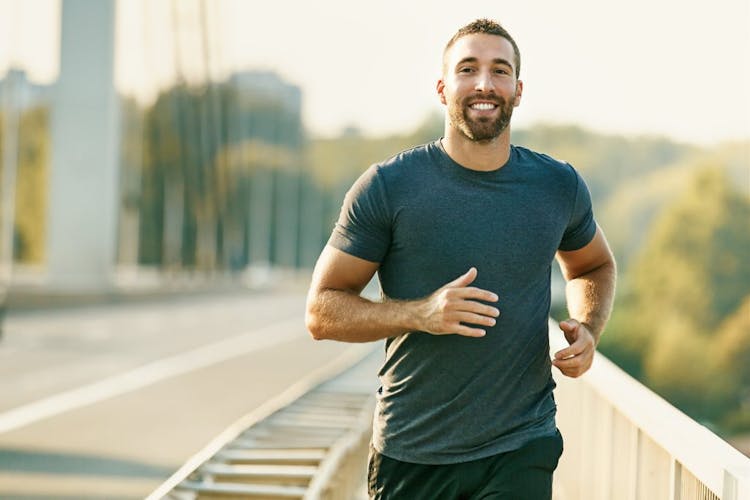 Smiling attractive man running across a bridge