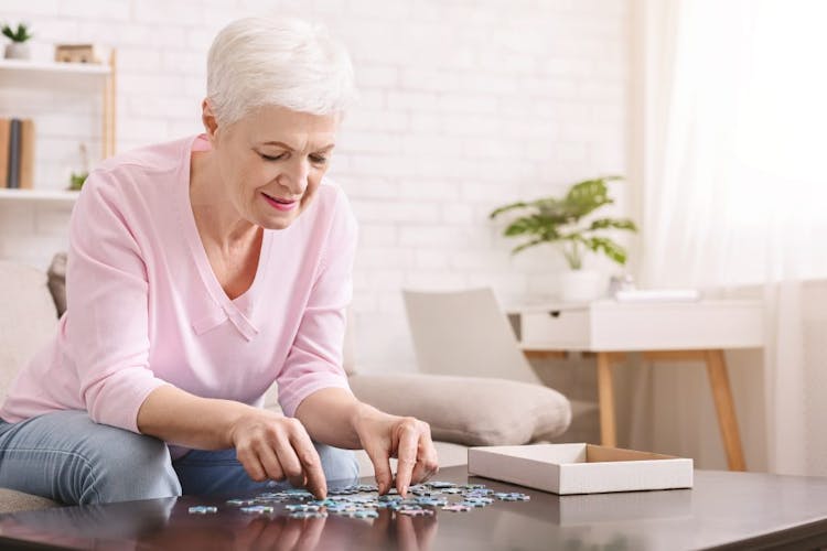 An elderly woman with white hair doing a puzzle