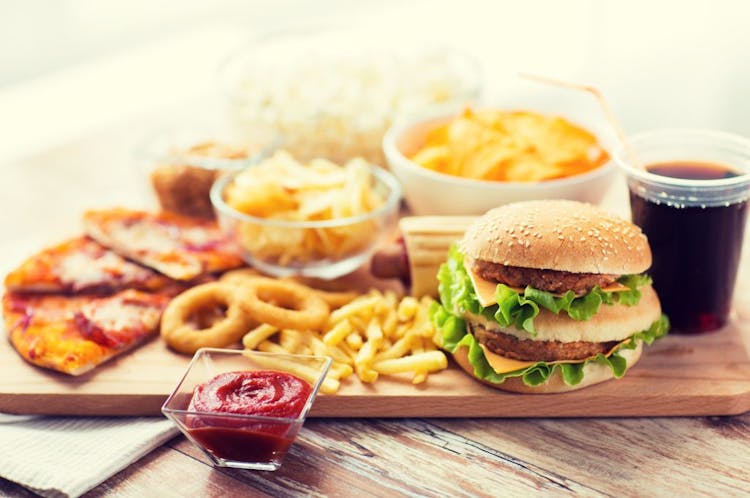 An image of unhealthy foods, such as fast food, cheeseburgers, French fries, onion rings, pizza, ketchup and soda