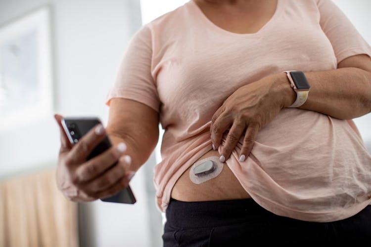 An obese olderly woman checking her blood sugar levels through a glucose monitor 