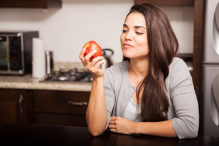A young woman chewing and eating an apple