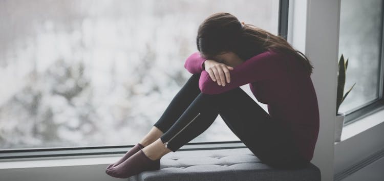 Image of a depressed woman with her head in her arms
