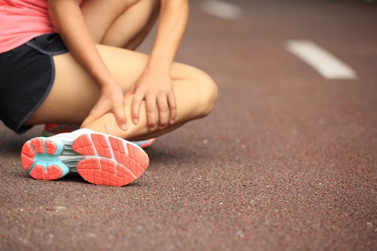 A woman having a leg cramp after running on a track