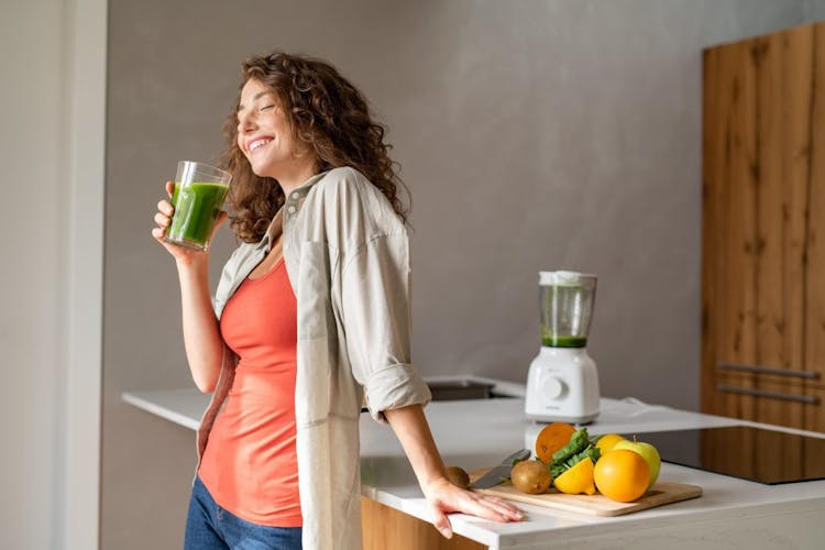 A young woman drinking fresh juice made from fruits and vegetables