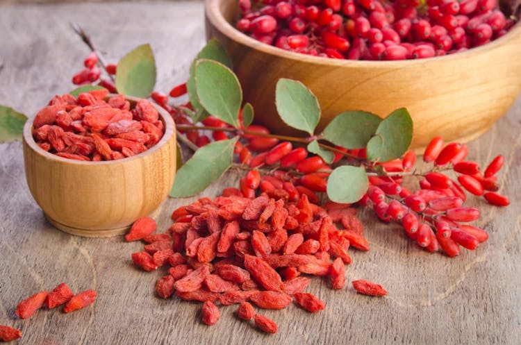 An image of goji berries in a bowl on a brown background