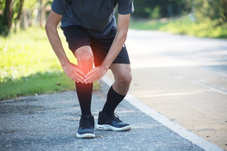 A male runner holding his shin splints in pain 