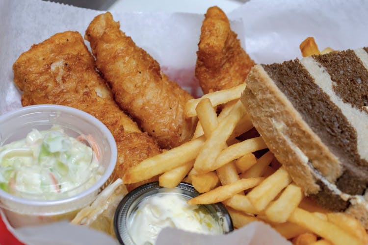 An image of fish fry foods such as fried fish, coleslaw, French fries and bread