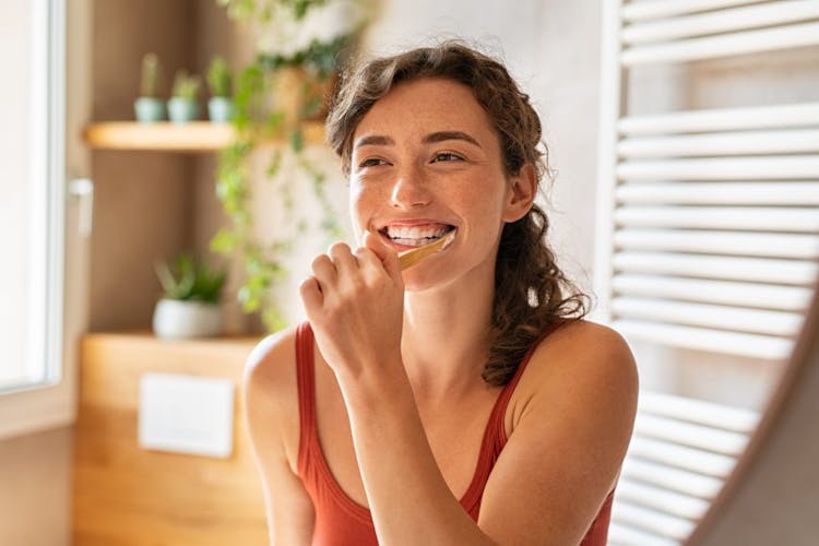 A smiling young woman brushing her teeth
