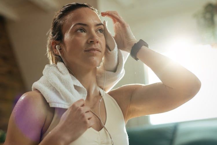 A young woman wiping sweat from her forehead after exercising 