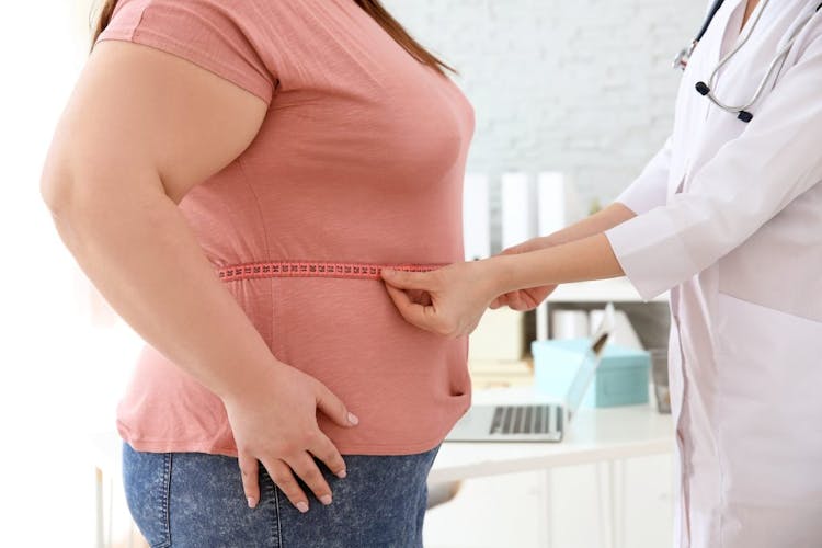 An image of a doctor measuring the circumference of an obese woman's abdomen