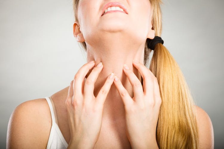 A lady scratching her neck with both hands due to itchiness of a neck rash