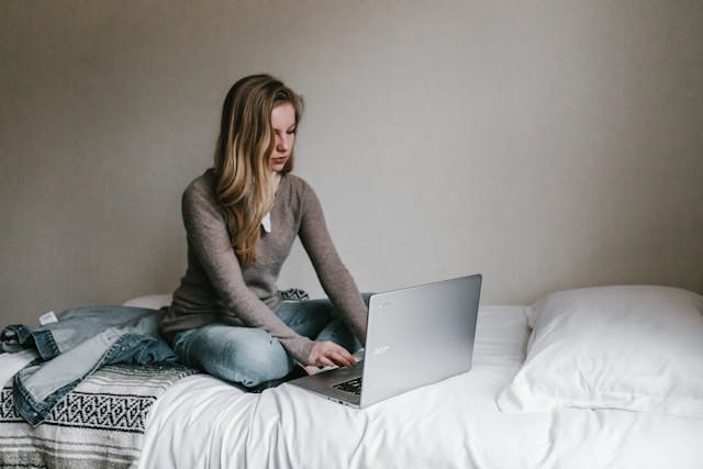 Woman sitting on the bed and using her laptop