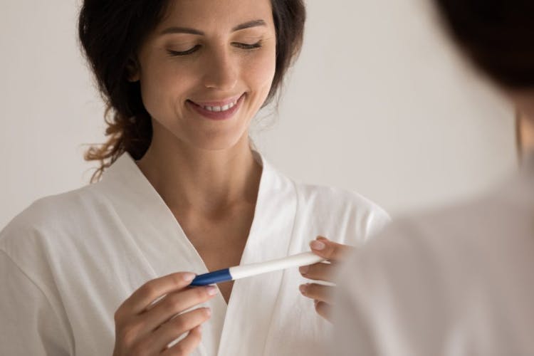 A happy woman holding a pregnancy test result