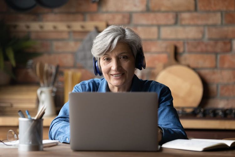 a middle age woman working in front of laptop and smiling at the camera