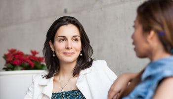 A woman smiling at her friend as they talk to each other