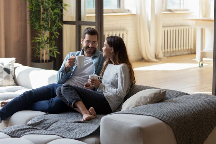 A couple talking over a cup of tea on a big sofa in a living room