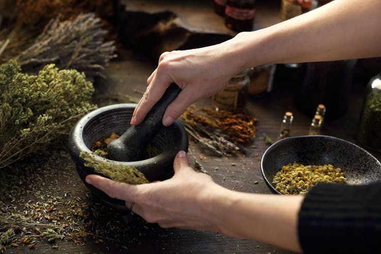 A person using mortar and pestle, grinding dry herbs
